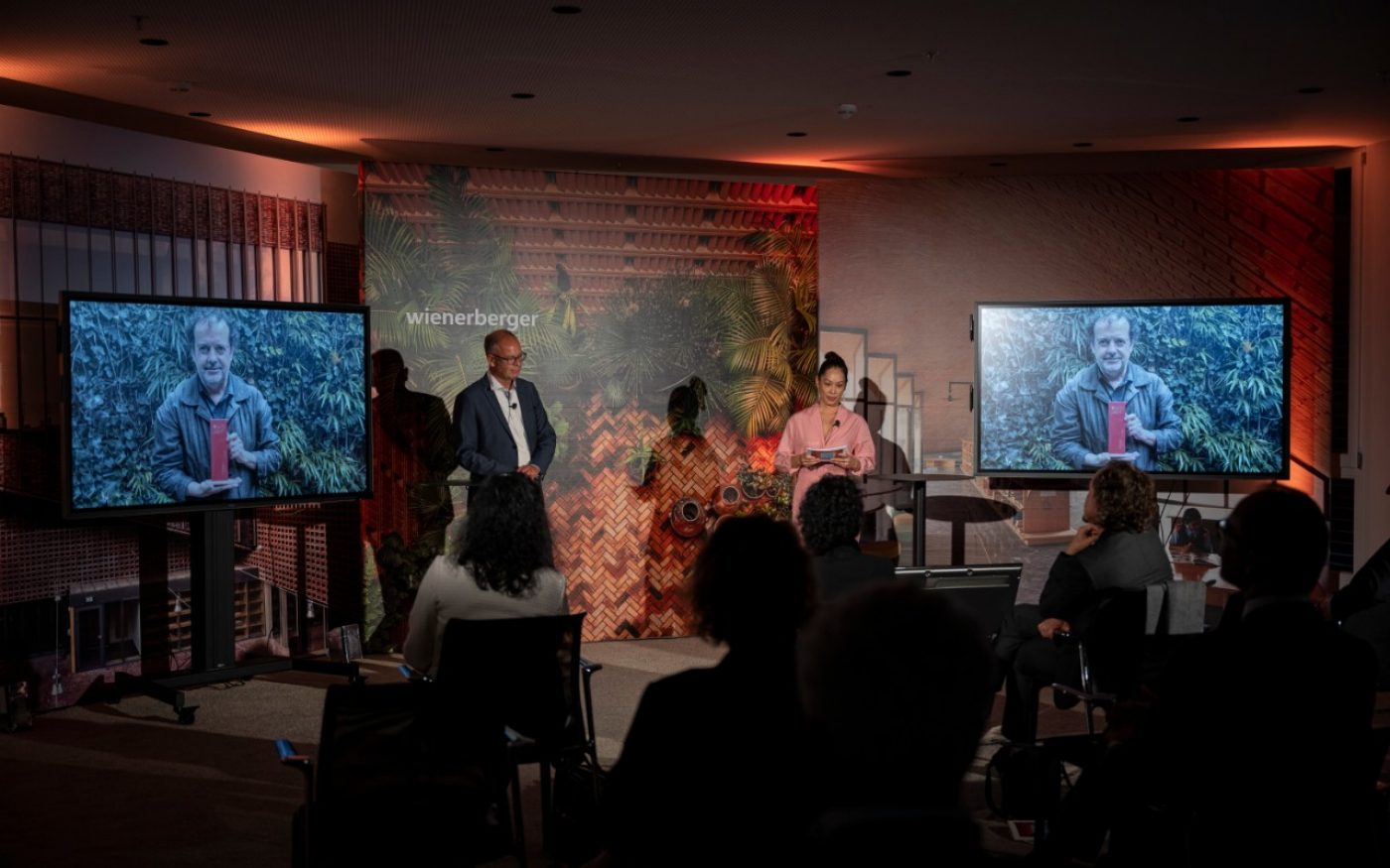 Heimo Scheuch and Miriam Hie on stage, picture of Mauricio Rocha with the trophy on screen