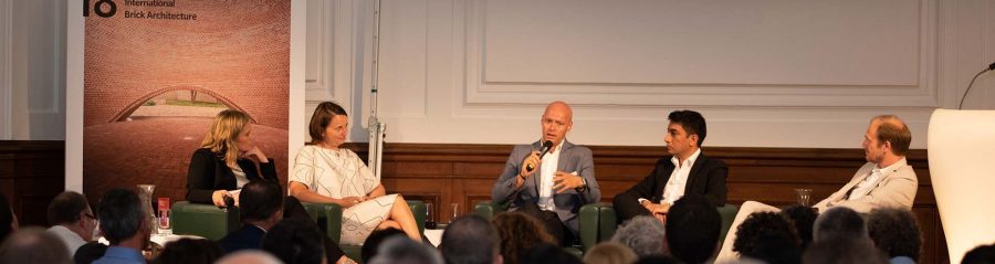 guests listen to discussion, panel sitting on stage