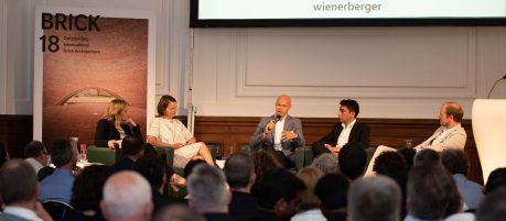 guests listen to discussion, panel sitting on stage